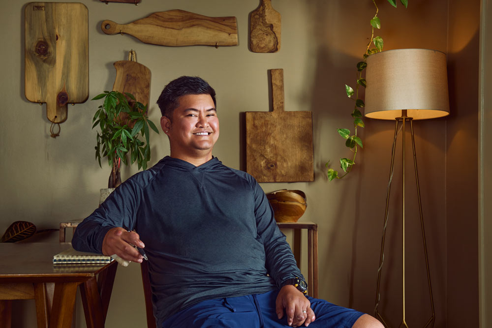Michael Mengote, a young man with black hair, sits with his elbow propped up on a table