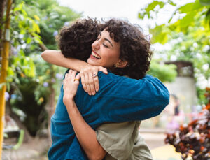 Two women hugging each other in the park.